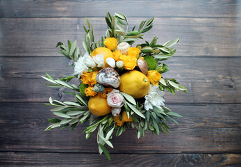 A bouquet of asters, yellow roses, real lemons, shells and olive leaves on a wooden background. The concept of gifts and congratulations for birthdays and various holidays. A pleasant surprise.