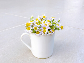 Bouquet of beautiful daisy flowers in white mug on grey tile background, decorated home, vintage tone.