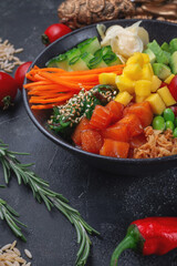Hawaii salmon poke with vegetables with ginger, mango, cucumber and avocado, rice, seaweed, tomato. Asian salmon poke on dark stone background.