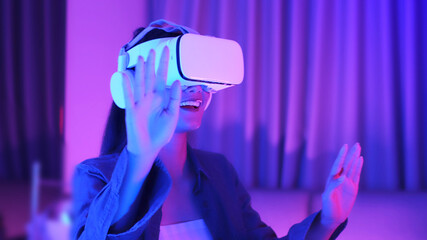 Young asian woman is using virtual reality headset. Neon light studio portrait. Concept of virtual...