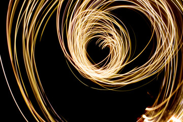 Yellow light swirl on black background. Long exposure photo.