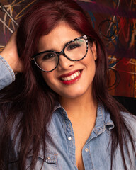 Chica latina con lentes sonrisa mirando al frente labios rojos retrato tocando su cabello