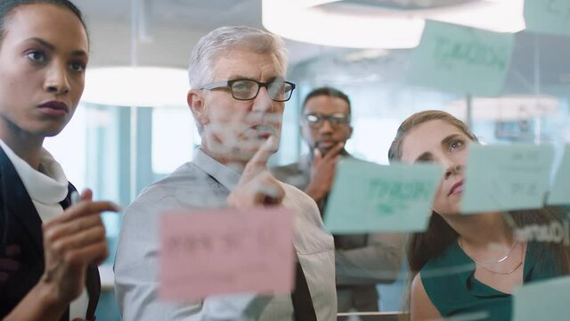 business people using sticky notes mature team leader man brainstorming with colleagues working on solution discussing strategy for project deadline teamwork in office management meeting 4k