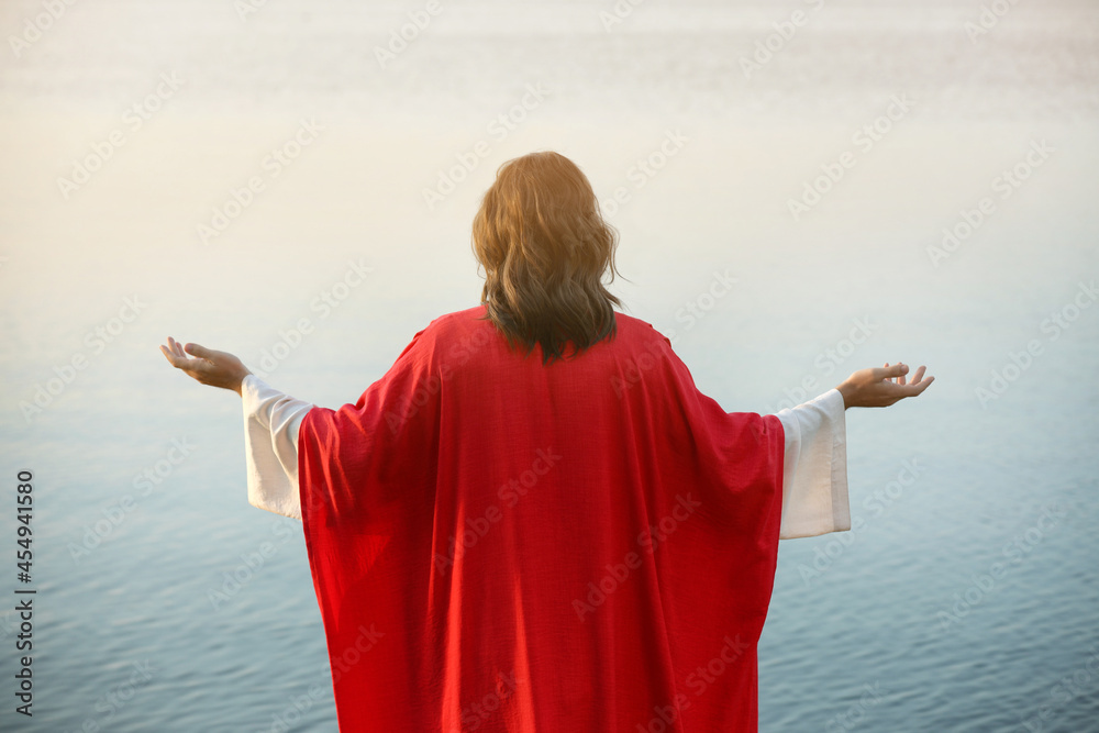 Wall mural Jesus Christ near water outdoors, back view