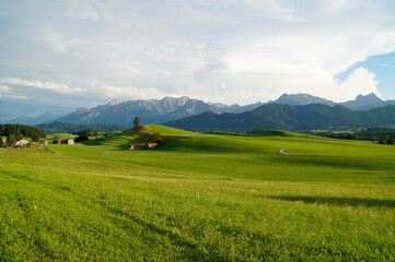 a scenic Bavarian countryside surrounded by succulent green meadows in Allgau or Allgaeu region in...