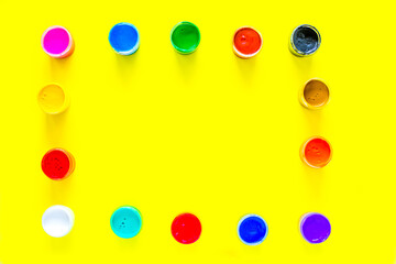 The paint cans are arranged in rectangles along the edge of the photo of different colors on a...