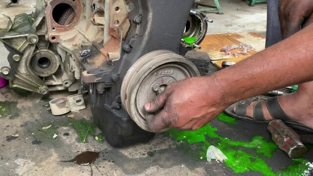 Mechanic removing car engine oil pump pully for repair