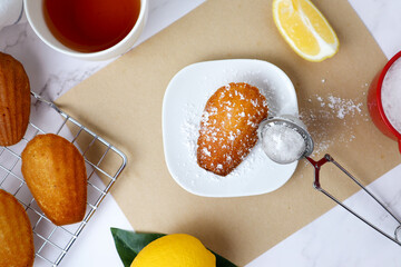 Vanilla madeleines with sugar icing on top -  flat lay french sweet cake on the marble table