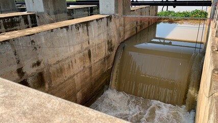 embankment river, dam,After the heavy rain, the turbid water was flowing strong through the drainage door. Concept flood protection