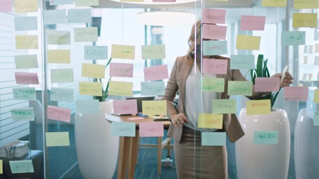 beautiful business woman using sticky notes brainstorming ideas planning strategy problem solving with creative mind map working on solution in office 4k