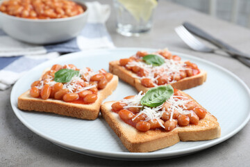 Toasts with delicious canned beans on light grey table
