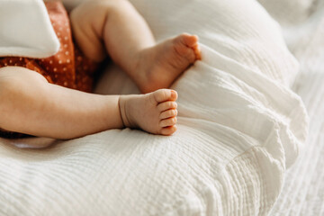 Closeup of barefoot baby feet on white muslin blanket.