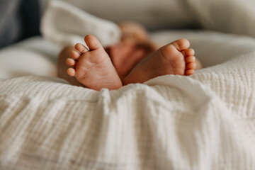 Closeup of barefoot baby feet on white muslin blanket.