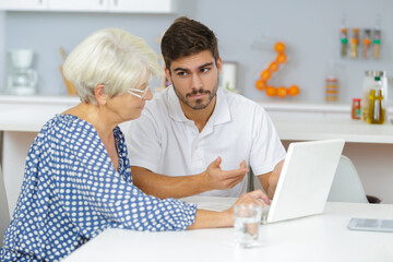 Obraz premium grandmother and grandson watching family pictures on laptop