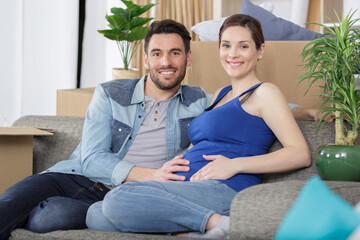 Obraz premium happy pregnant couple with belongings at new home