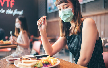 Asian woman sitting separated in restaurant eating food .keep social distance for protect infection...