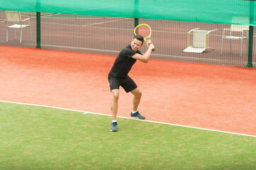 Tennis player with a tennis racket ready to parry a blow on an artificial tennis court.