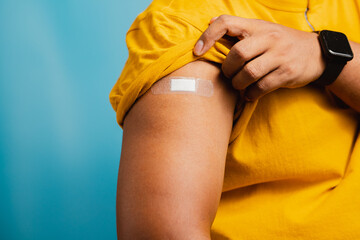 A teenage man shows his sleeve with a bandage after vaccination. medical first aid concept and health care
