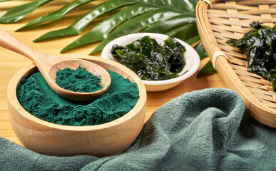 laminaria or kelp seaweed and spirulina powder in wood bowl and spoon background. spirulina powder with konbu and alga food on wood table background.                            © boommaval