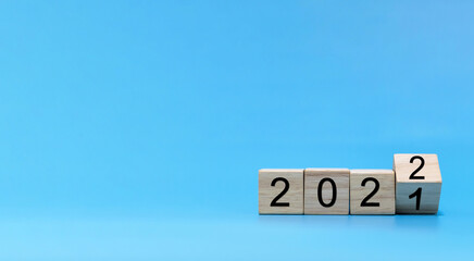 Happy New Year 2022 celebration. number written on wooden cube block stack on blue background,...