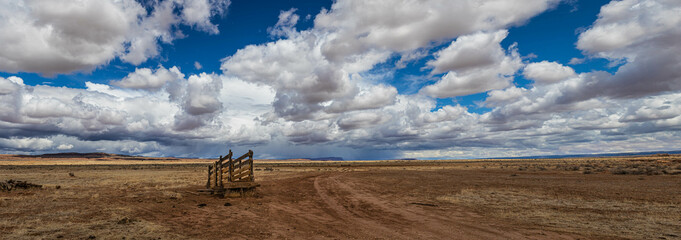 A panorama of an old corral, abandoned in the desert of Arizona under a blue sky with bright white...