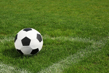 Football ball on green field grass outdoors. Space for text