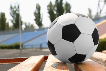 Fototapeta na wymiar Football ball on wooden bench in stadium