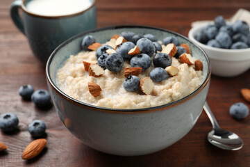 Tasty oatmeal porridge with blueberries and almond nuts on wooden table