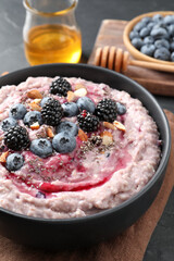Tasty oatmeal porridge with toppings in bowl served on table