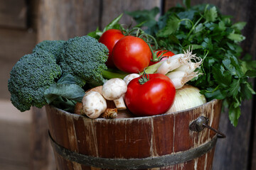 Hand-picked tomatoes, broccoli, green onions, parsley in a rustic bucket