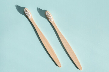 Two eco friendly bamboo wooden toothbrushes on a light blue background. Hard light. View from above