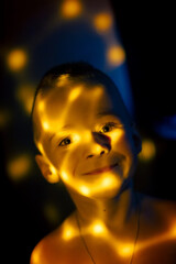 Little boy in the rays of yellow light. Smiling boy in dots of yellow light