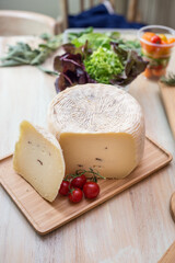 Cheese and cherry tomato isolated on wooden cutting board. Vertical