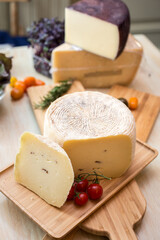 Cheese and cherry tomato isolated on wooden cutting board. Vertical