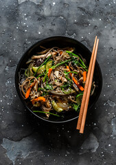 Buckwheat noodles with chicken breast, vegetables and mushrooms - delicious asian style lunch on a dark background, top view