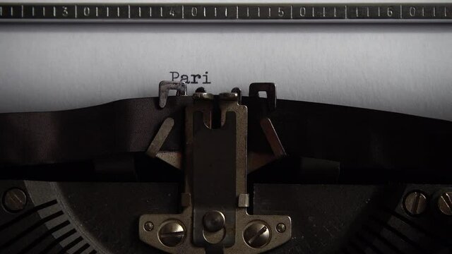 Typing city name Paris on an old typewriter. Close up.