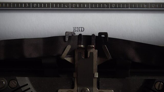 Typing word End on retro typewriter. Close up.