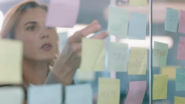 beautiful business woman using sticky notes brainstorming ideas planning strategy on glass whiteboard problem solving with creative mind map working on solution in office 4k