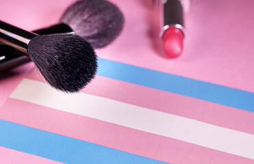 lipstick and make-up brushes close up view over a transgender flag