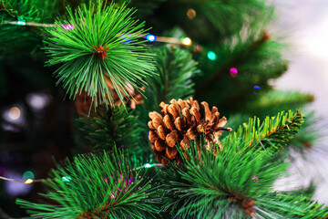 Fragment of a Christmas tree made of artificial materials and a natural pine cone. Festive postcard. Template for the designer