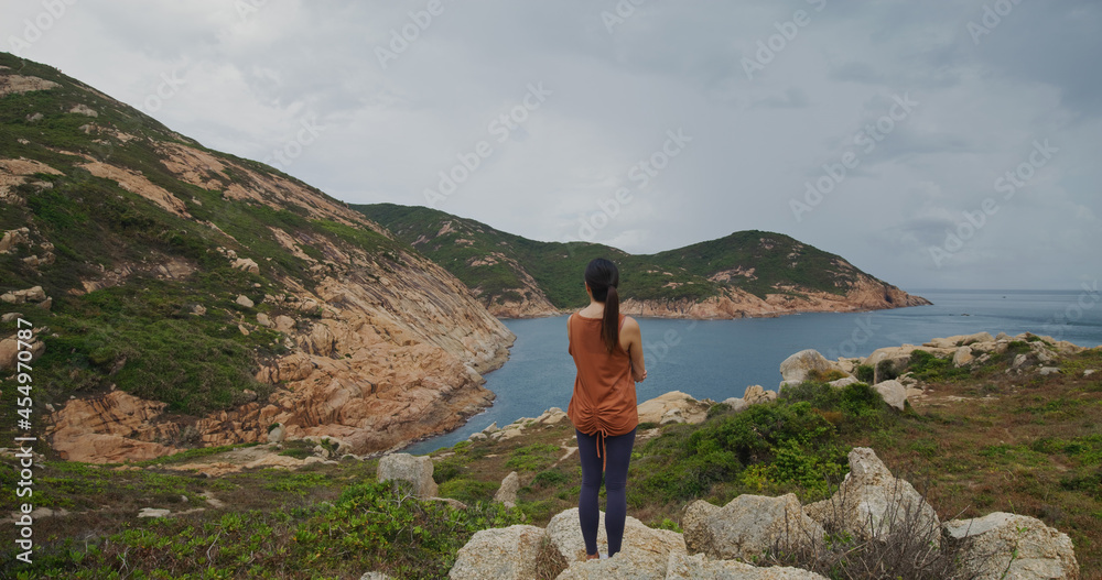 Wall mural woman stand on the rock and enjoy the view