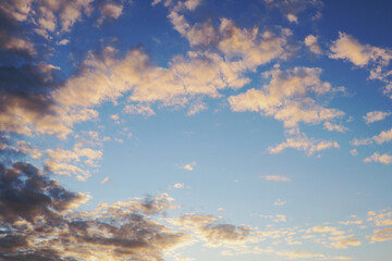 Blue sky, light and dark clouds at sunset. Cloudscape background or wallpaper. End of a sunny summer day