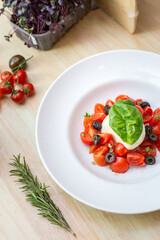 Plate with fresh salad with tomatoes, basil leaves and mozzarella 