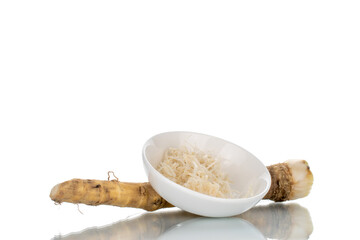 One whole spicy horseradish root and grated horseradish in a white saucer, close-up isolated on white.