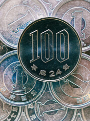 100 yen lies on a pile of Japanese 1 yen coins. Close up. View from above. Catchy vertical illustration. News about the economy, money and finance of Japan. Macro