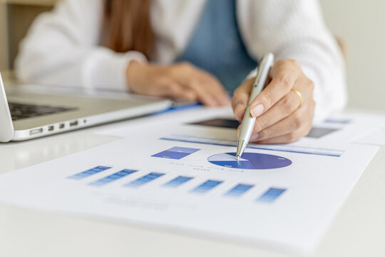 Businesswoman pointing to a pie chart document showing company financial information, she sits in her private office, a document showing company financial information in chart form. Financial concepts