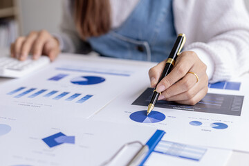 A financial scholar is pointing at a document with a pen, she is analyzing and checking company financial data for accuracy before presenting it to the meeting. Financial audit concept.