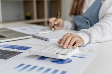 Woman holding a pen pointing to documents on a desk, she is a financial scholar, she is checking company financial documents for accuracy before presenting them to executives. Financial audit concept.