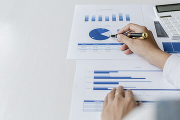 Woman holding a pen pointing to documents on a desk, she is a financial scholar, she is checking company financial documents for accuracy before presenting them to executives. Financial audit concept.