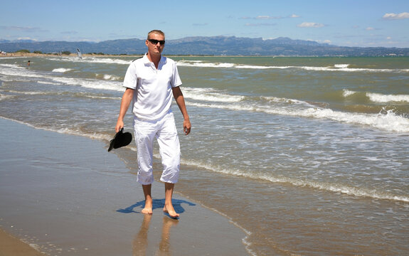 A young man walks along the Balearic Sea at Riumar beach in Spain